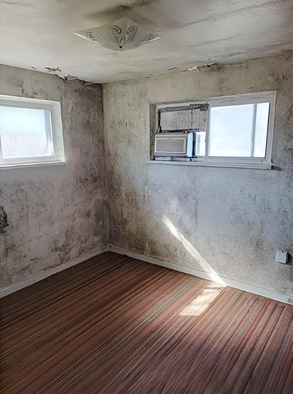 empty room featuring a healthy amount of sunlight, cooling unit, ceiling fan, and wood finished floors