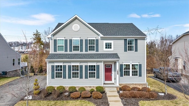 traditional-style house featuring roof with shingles and aphalt driveway