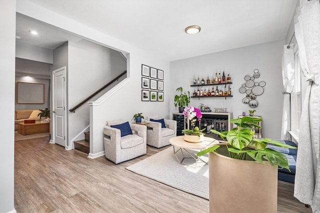 living room with a bar, stairway, wood finished floors, and baseboards