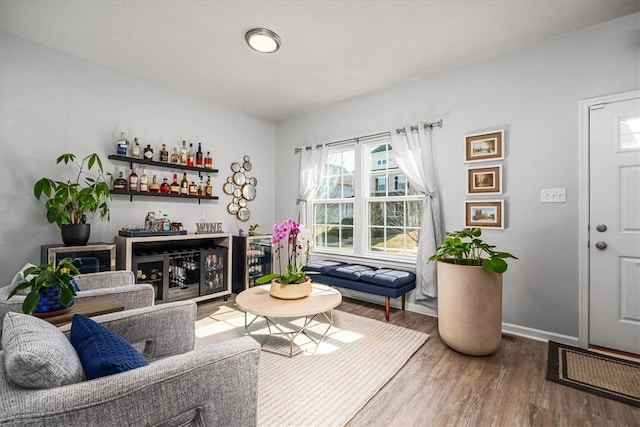 living room with a bar, wood finished floors, and baseboards