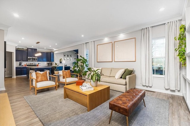 living area with crown molding, recessed lighting, light wood-type flooring, and baseboards