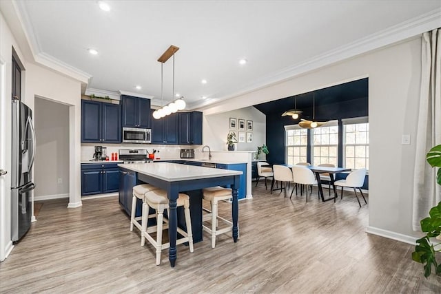 kitchen with light countertops, appliances with stainless steel finishes, a kitchen bar, crown molding, and blue cabinets