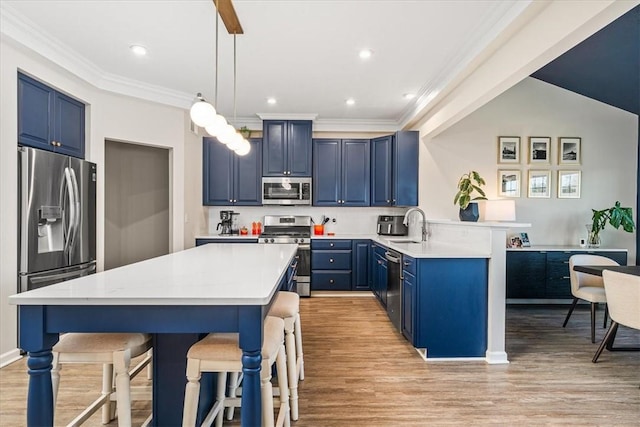 kitchen with a peninsula, blue cabinetry, a breakfast bar area, and stainless steel appliances