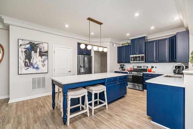 kitchen with visible vents, blue cabinetry, a center island, appliances with stainless steel finishes, and a sink