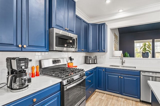 kitchen featuring a sink, blue cabinets, appliances with stainless steel finishes, and crown molding