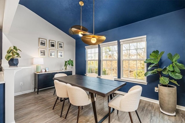 dining room featuring baseboards, wood finished floors, and vaulted ceiling