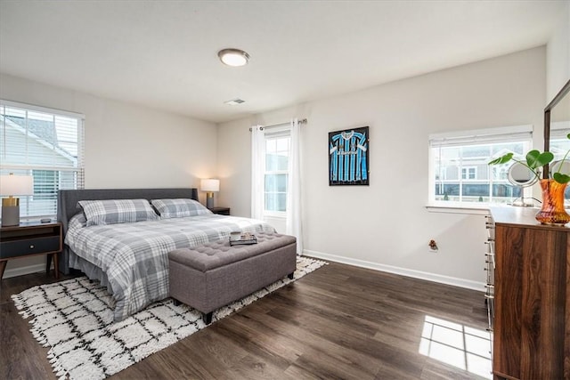 bedroom featuring visible vents, multiple windows, baseboards, and wood finished floors