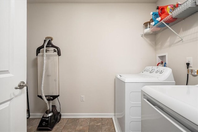 clothes washing area featuring laundry area, separate washer and dryer, and baseboards