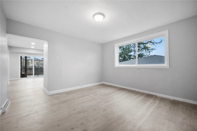 spare room with wood finished floors, baseboards, and a baseboard radiator