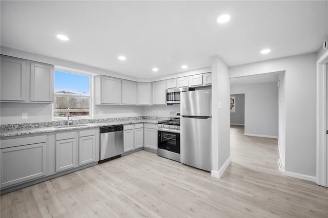 kitchen featuring a sink, light wood-style floors, appliances with stainless steel finishes, and gray cabinetry