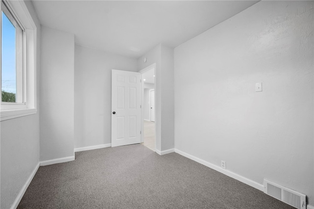 carpeted spare room with visible vents and baseboards