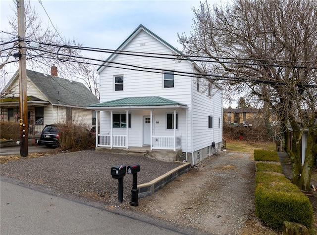 view of front of property featuring covered porch, driveway, and metal roof