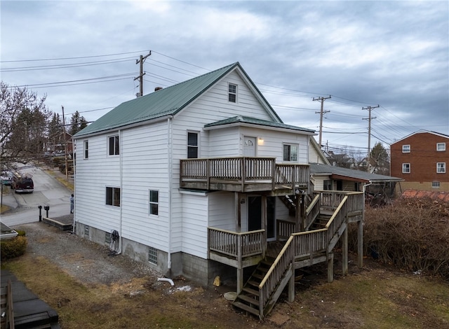 back of house with metal roof, a deck, and stairway