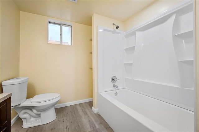 bathroom with vanity, wood finished floors, baseboards, shower / washtub combination, and toilet