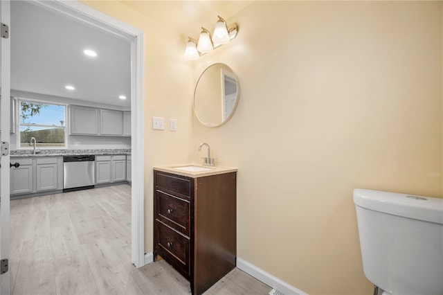 bathroom featuring vanity, toilet, wood finished floors, and baseboards