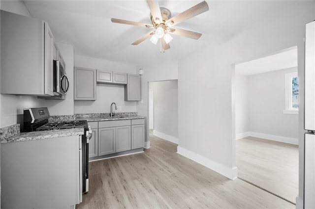 kitchen featuring a sink, light wood-type flooring, appliances with stainless steel finishes, and gray cabinetry