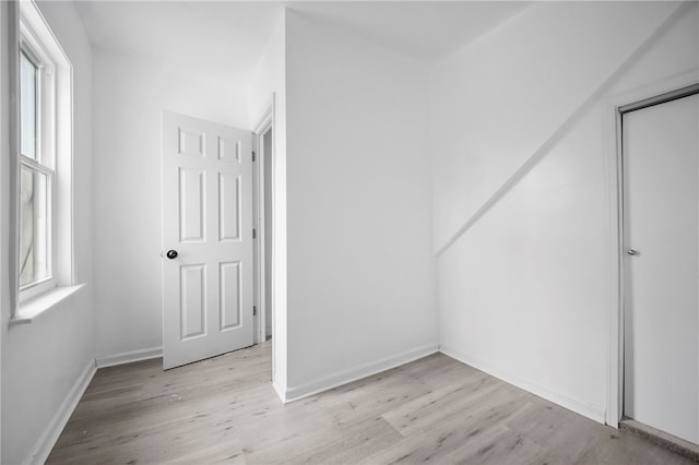 interior space with baseboards, multiple windows, and wood finished floors