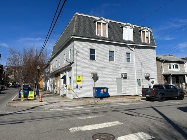 view of side of property with mansard roof and roof with shingles