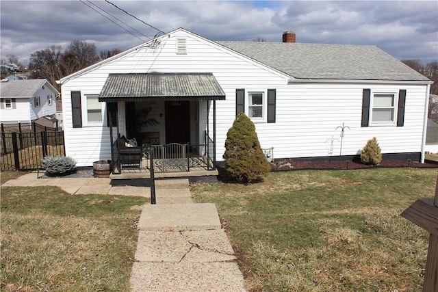 rear view of house with fence, a porch, a chimney, a shingled roof, and a lawn