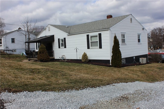 exterior space with a chimney, a front lawn, and roof with shingles