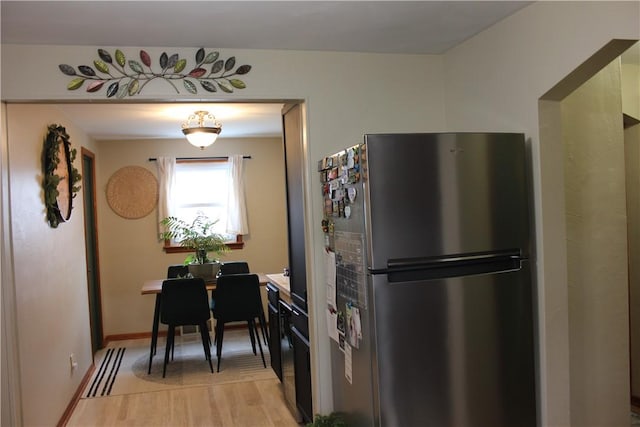 kitchen featuring light wood finished floors, freestanding refrigerator, and baseboards