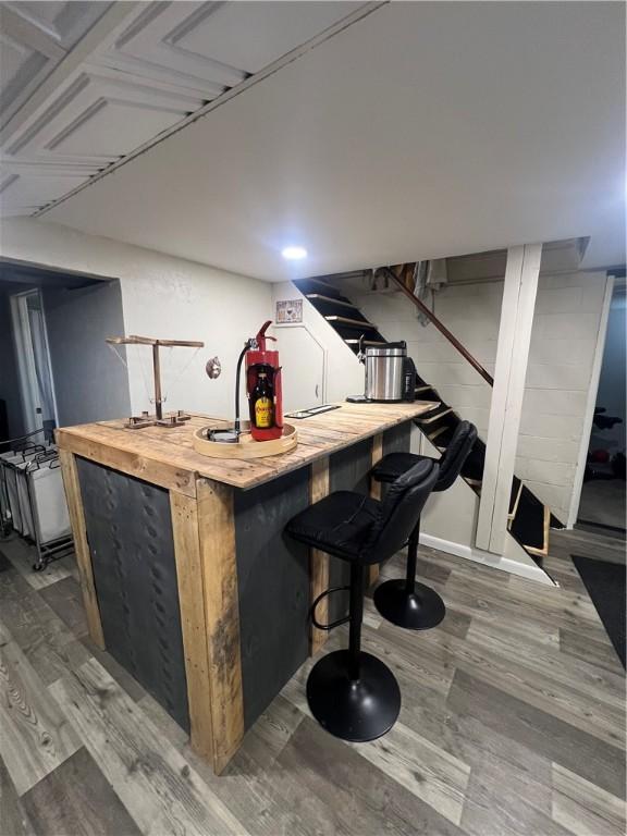 bar featuring indoor bar, wood finished floors, and stairs