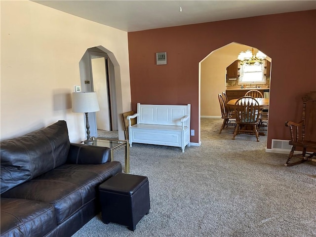 carpeted living room featuring visible vents, baseboards, and arched walkways