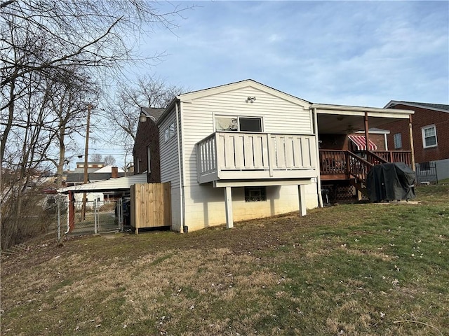 back of property with a lawn, a wooden deck, and a gate