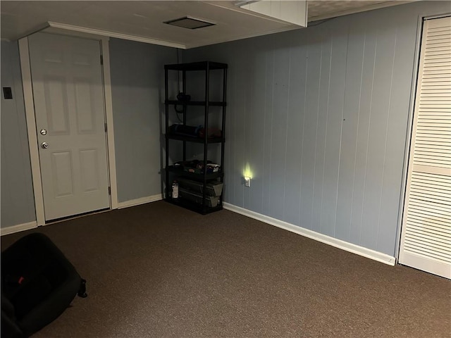 below grade area featuring baseboards and dark colored carpet