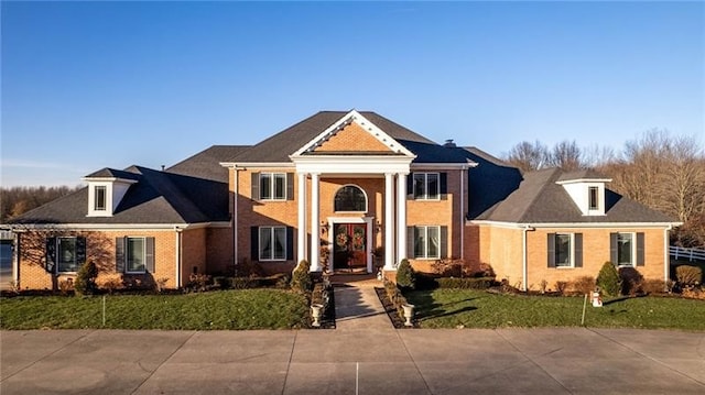 neoclassical home featuring brick siding and a front lawn