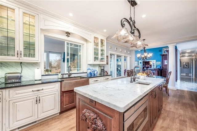 4605 Whippoorwill Dr, Hermitage, PA 16148 - kitchen featuring stainless steel microwave, a chandelier, dark stone countertops, pendant lighting, and glass insert cabinets
