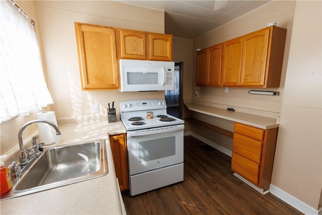 kitchen featuring white appliances, light countertops, dark wood-type flooring, and a sink