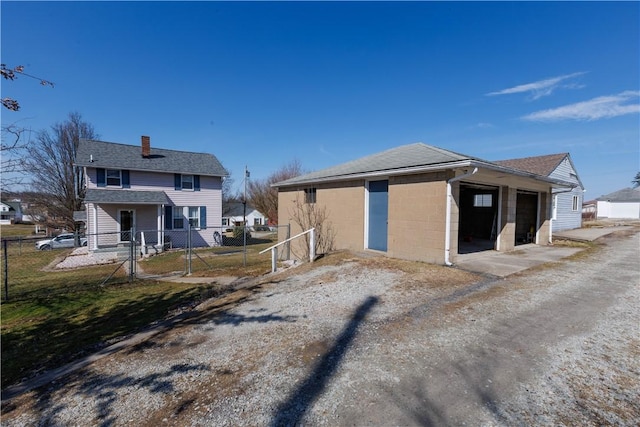 exterior space with a gate, dirt driveway, fence, concrete block siding, and a chimney