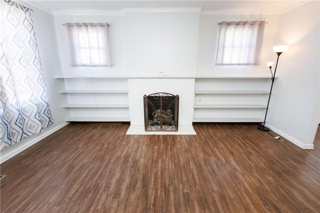 unfurnished living room with baseboards, a fireplace, wood finished floors, and crown molding