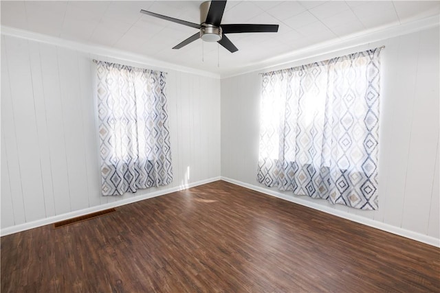 empty room featuring ceiling fan, visible vents, baseboards, and wood finished floors