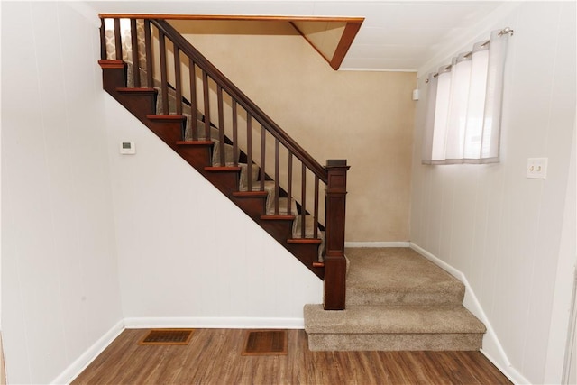 stairway with visible vents, baseboards, and wood finished floors