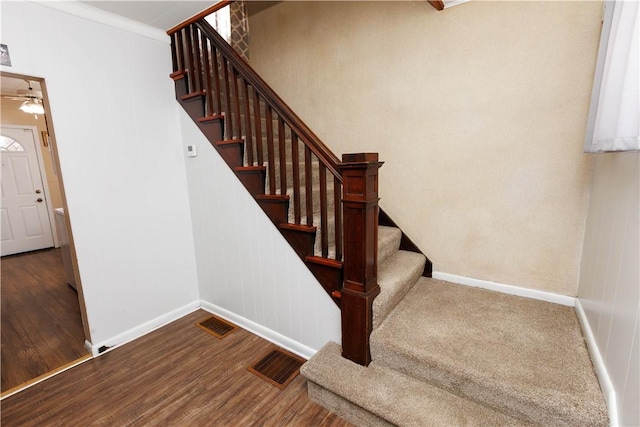 stairs featuring crown molding, wood finished floors, visible vents, and baseboards