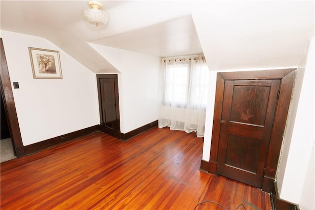 additional living space with vaulted ceiling, baseboards, and wood-type flooring