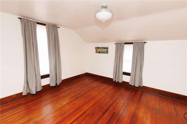 unfurnished room with dark wood-style floors, plenty of natural light, baseboards, and vaulted ceiling