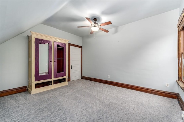 unfurnished bedroom featuring lofted ceiling, a ceiling fan, baseboards, and carpet floors