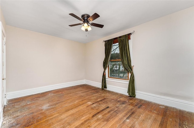 spare room featuring a ceiling fan, baseboards, and wood-type flooring