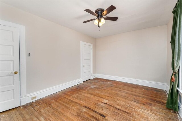 spare room with baseboards, light wood-style floors, and a ceiling fan