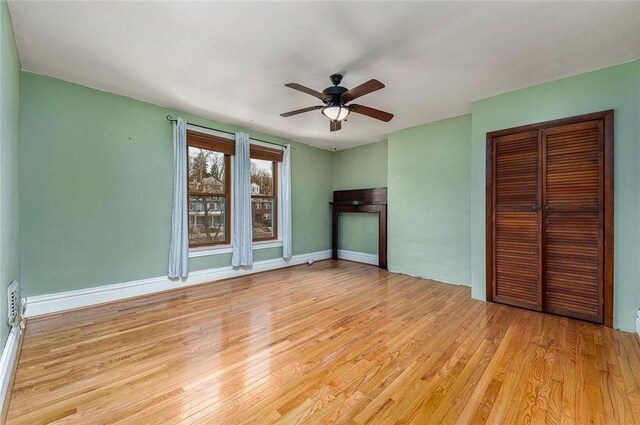 unfurnished bedroom with ceiling fan, a closet, baseboards, and wood finished floors