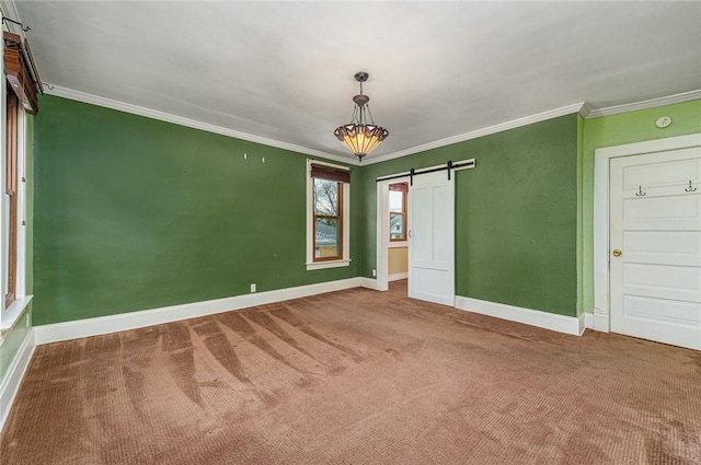 empty room featuring baseboards, carpet, crown molding, and a barn door