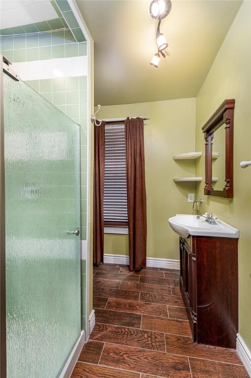 bathroom featuring a shower stall, vanity, baseboards, and wood tiled floor