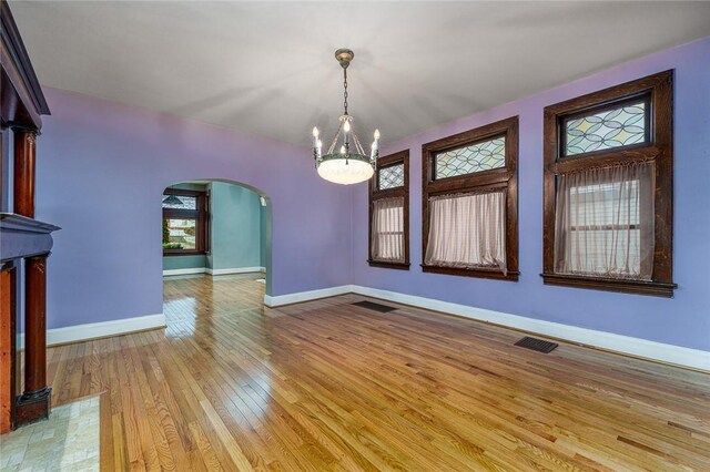 interior space with arched walkways, visible vents, baseboards, and wood-type flooring