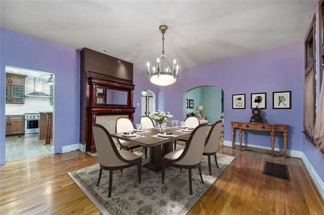 dining area featuring baseboards, arched walkways, visible vents, and hardwood / wood-style floors