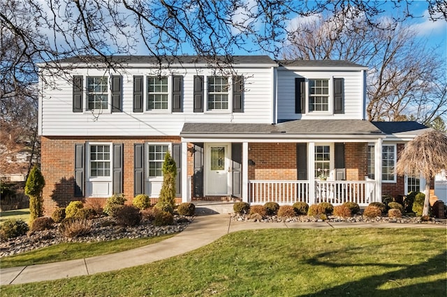 view of front facade featuring a front lawn, brick siding, and covered porch