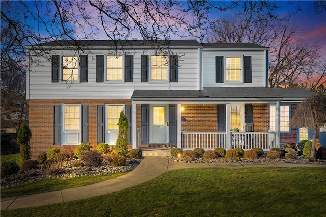 view of front of property with brick siding, a porch, and a front lawn