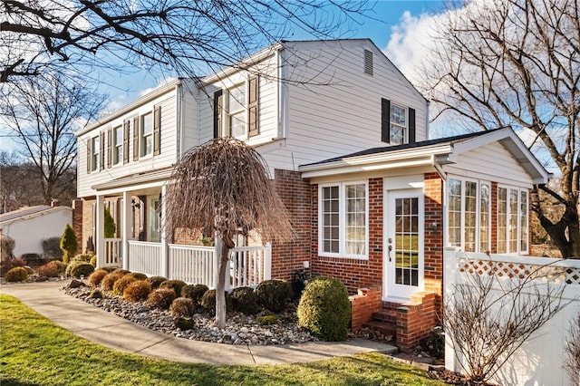 view of side of property featuring brick siding and a porch